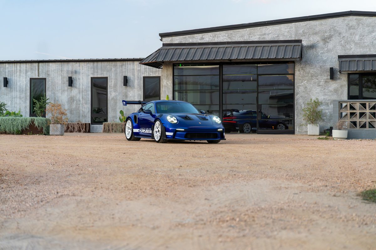 A blue 2025 Porsche 911 GT3 RS with white stripe livery and white racing rims.