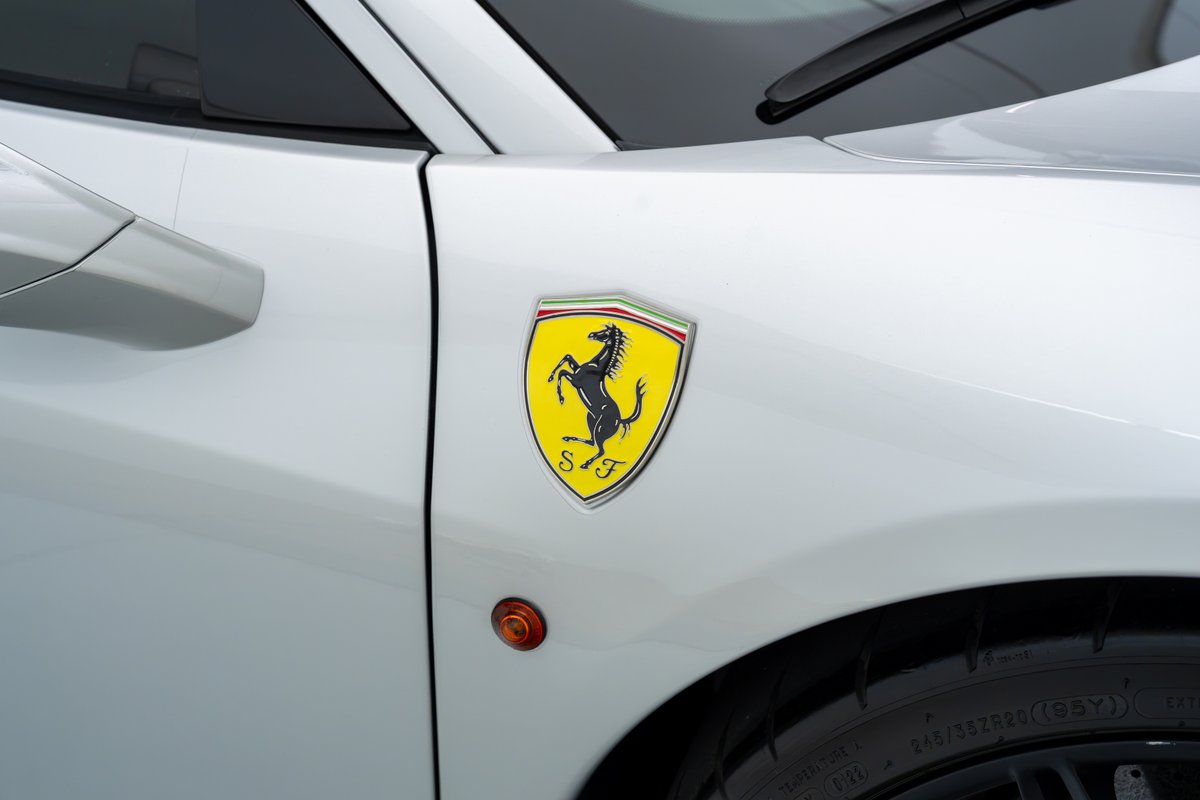 White 2015 Ferrari 458 Speciale fender with iconic yellow Prancing Horse emblem.