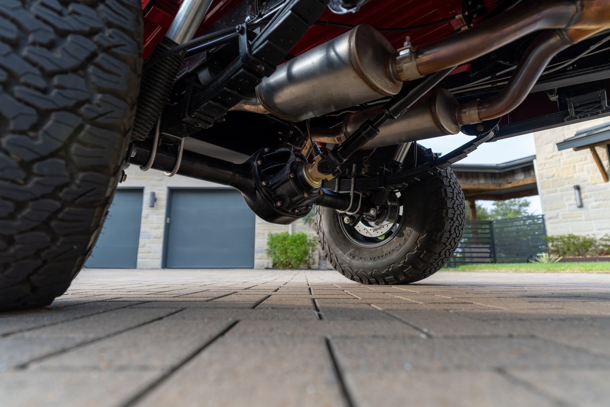 1966 Ford Bronco's detailed rear axle, leaf springs, and dual exhaust.