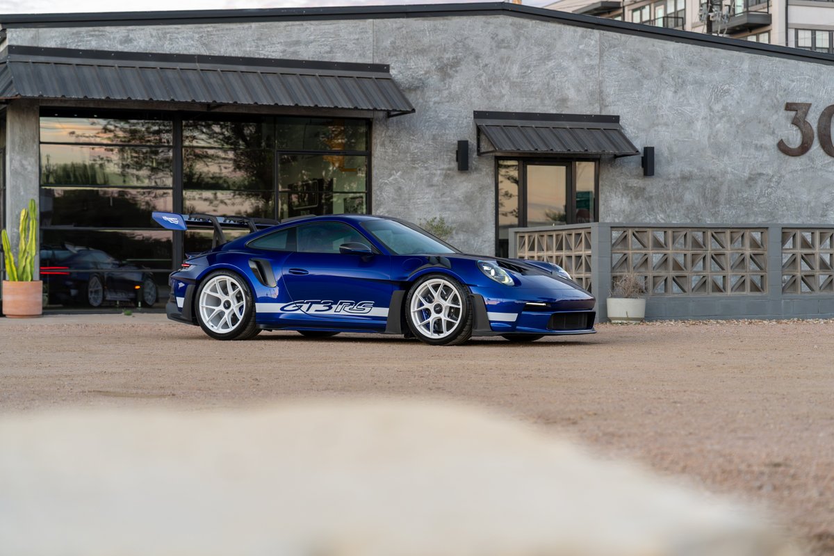 A blue 2025 Porsche 911 GT3 RS with white multi-spoke rims and white GT3 RS livery.