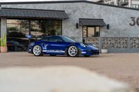 A blue 2025 Porsche 911 GT3 RS with white multi-spoke rims and white GT3 RS livery.