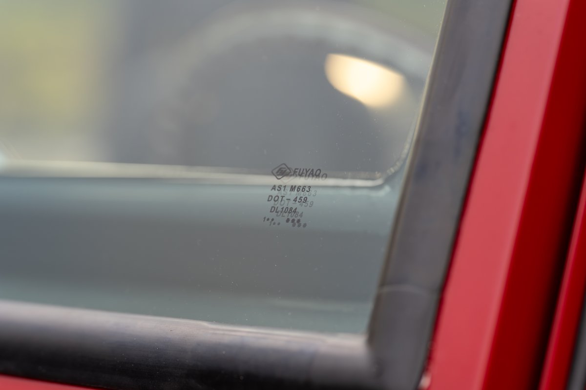 Close up of the AS1 M663 safety glass etching on a vintage red 1966 Ford Bronco.