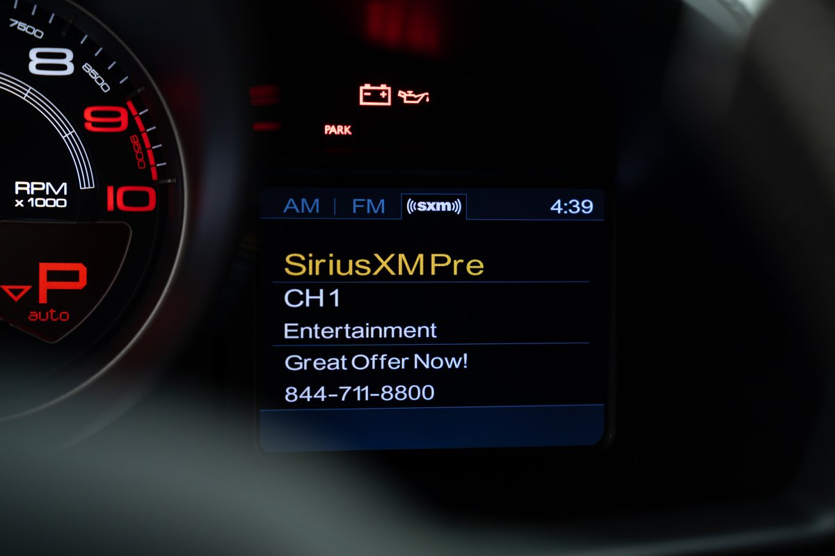 Close-up of a 2015 Ferrari 458 Speciale dashboard showing RPM gauge and SiriusXM display.