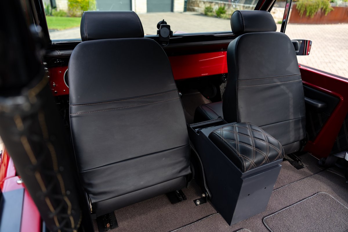 Black leather seats in a red 1966 Ford Bronco, featuring quilted diamond stitch armrest.
