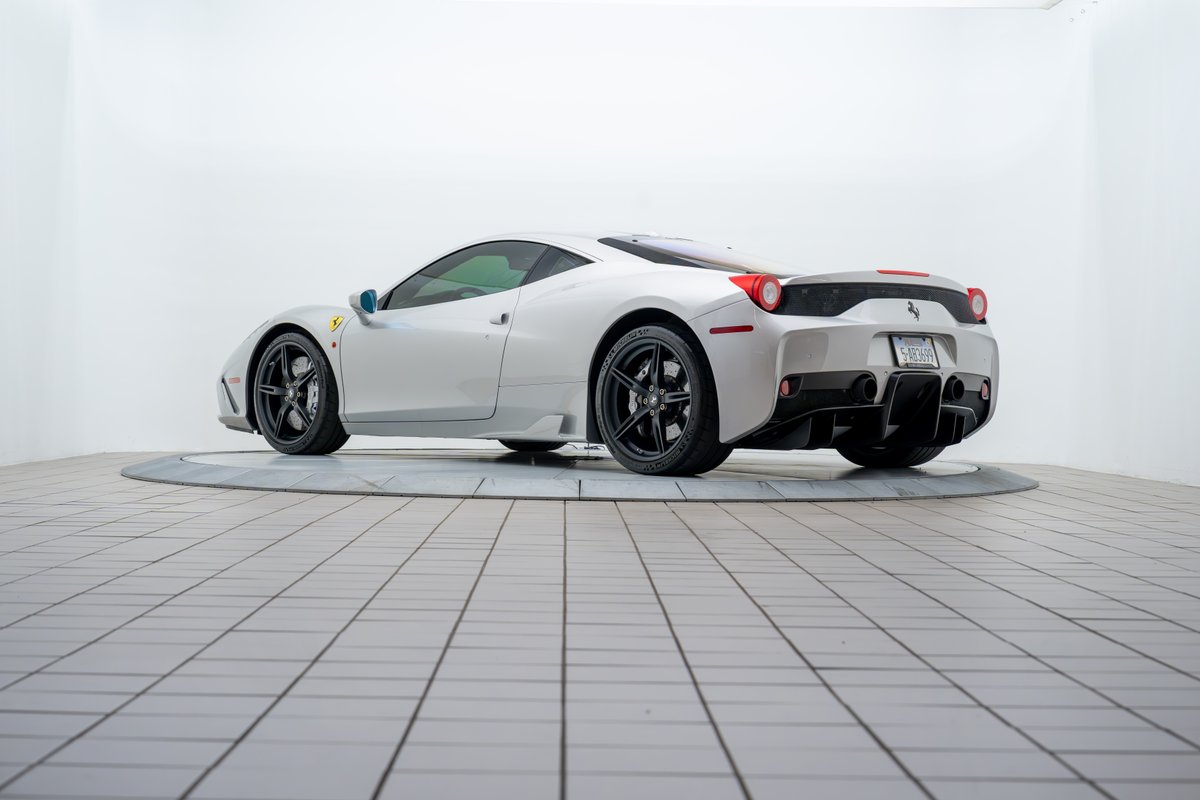 Rear view of a silver 2015 Ferrari 458 Speciale with black rims and quad exhaust.