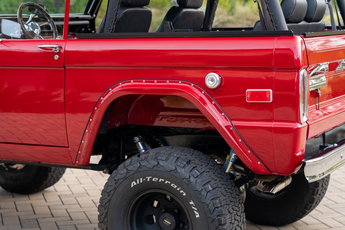 Red 1966 Ford Bronco by Atlas Broncos shows riveted fender flares and all-terrain tires.
