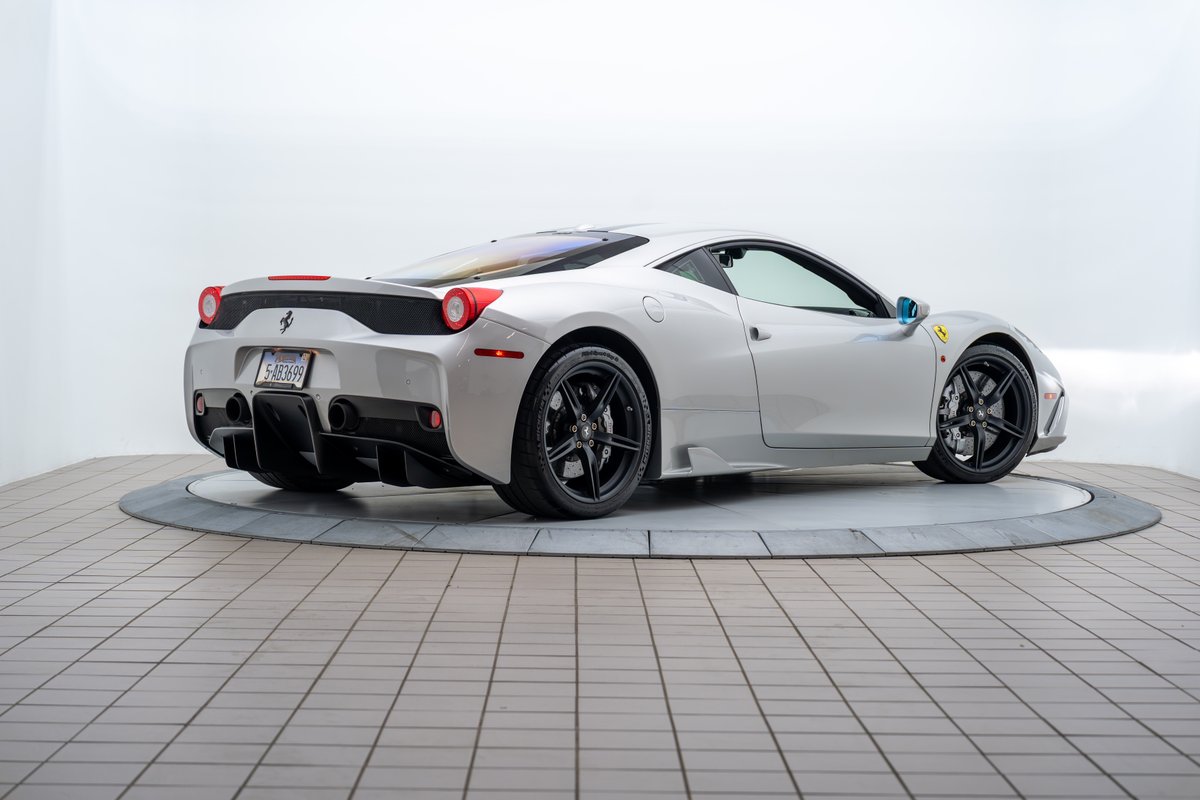 2015 Ferrari 458 Speciale in silver, rear 3/4 view, black rims, carbon fiber diffuser.