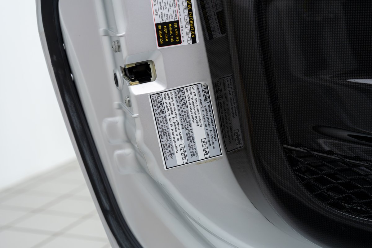2015 Ferrari 458 Speciale doorjamb with tire pressure warning stickers and carbon fiber trim.