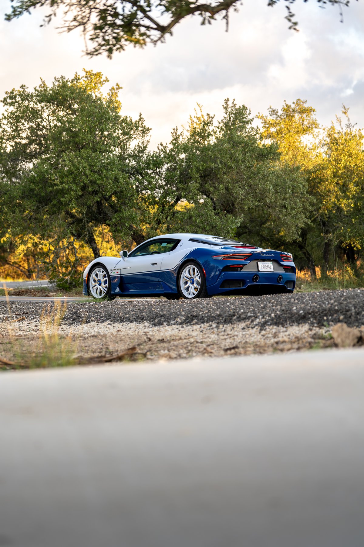 Rear 3/4 view of the 2024 Maserati MC20 Icona in blue and white, with white rims.
