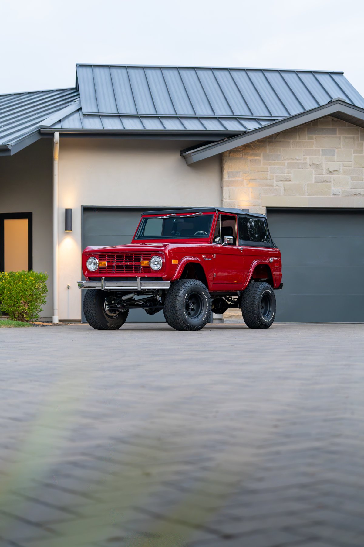 Red 1966 Ford Bronco by Atlas Broncos, lifted with black rims and off-road tires.