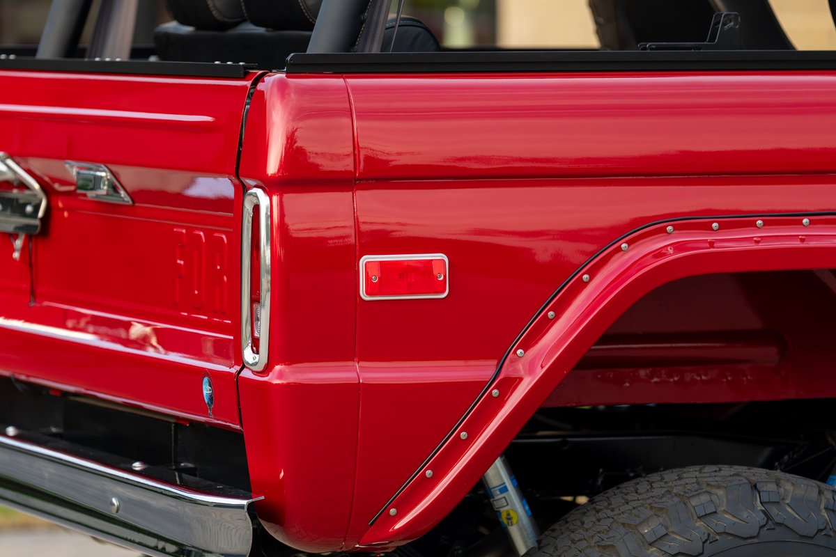 Close-up of a red 1966 Ford Bronco's rear fender trim and tail light.