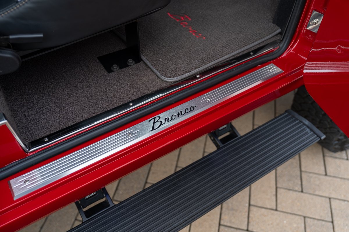 Red 1966 Ford Bronco with "Bronco" script door sill trim and running boards.