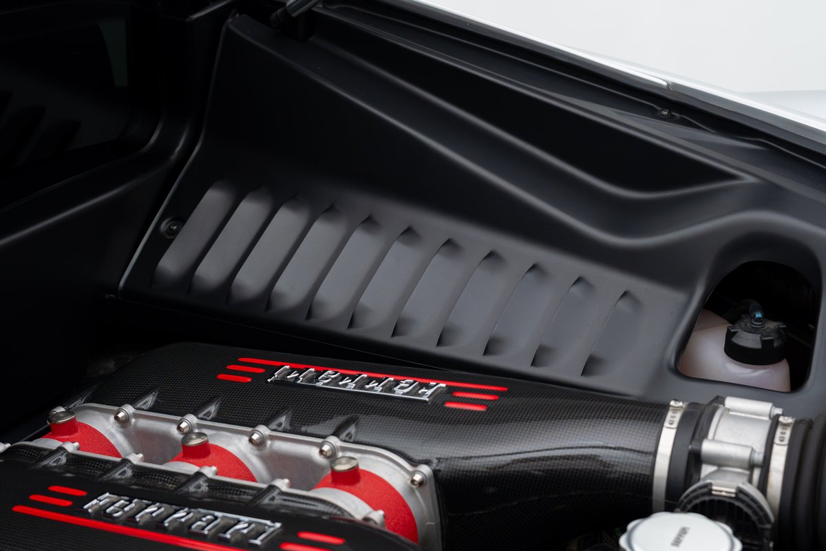 Close-up of the 2015 Ferrari 458 Speciale engine bay, featuring carbon fiber engine cover with red livery.