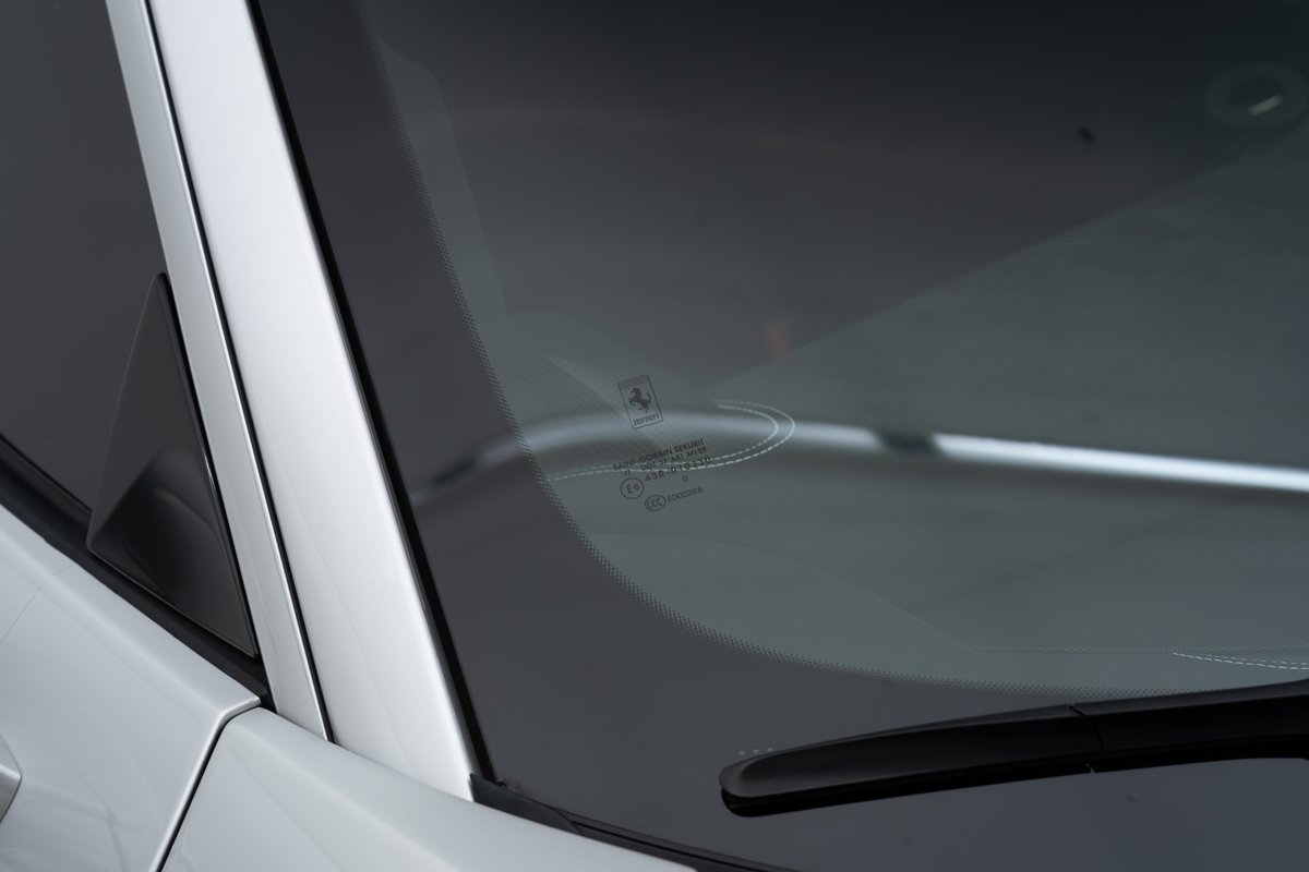 Close-up of a 2015 white Ferrari 458 Speciale windshield with manufacturer markings.