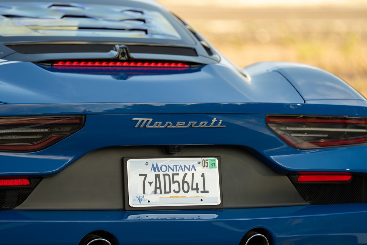 Close-up of the rear of a blue 2024 Maserati MC20 Icona, showcasing the badge, taillights, and license plate.