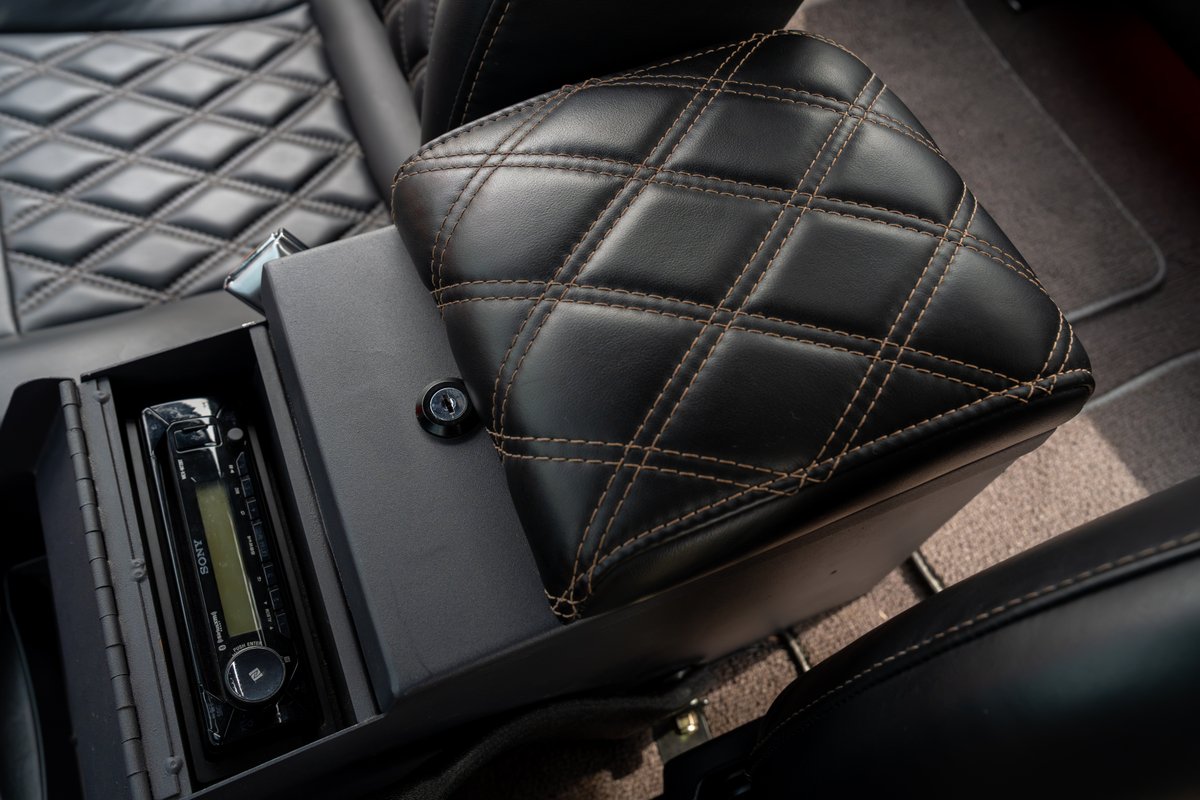 Diamond-stitched black leather armrest over a center console with a vintage Sony stereo in a 1966 Ford Bronco.