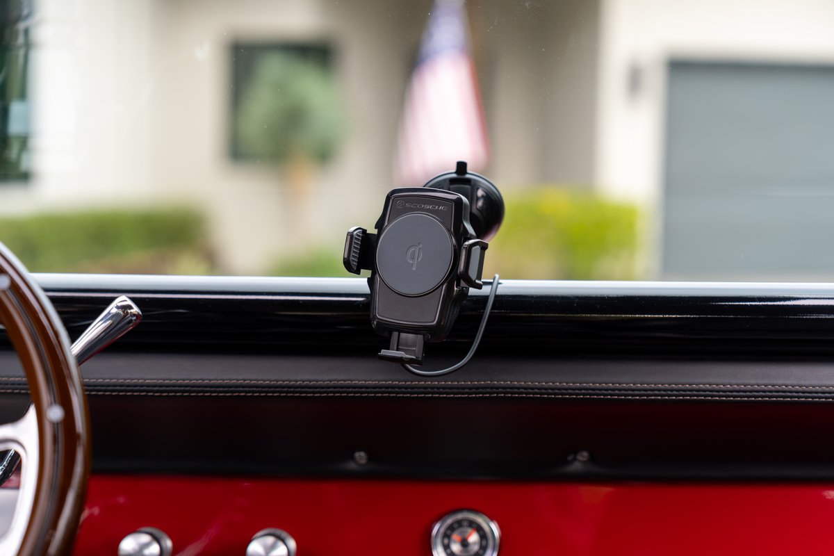 1966 Ford Bronco interior: Wireless charging phone mount on dashboard, red upholstery, wood steering wheel.