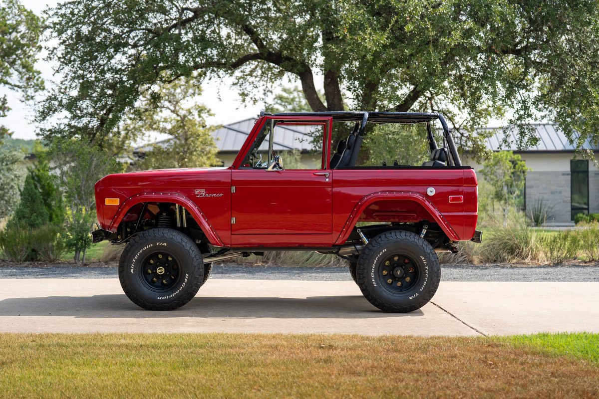 Red 1966 Ford Bronco by Atlas Broncos, showcasing its lift kit, all-terrain tires, and beadlock rims.