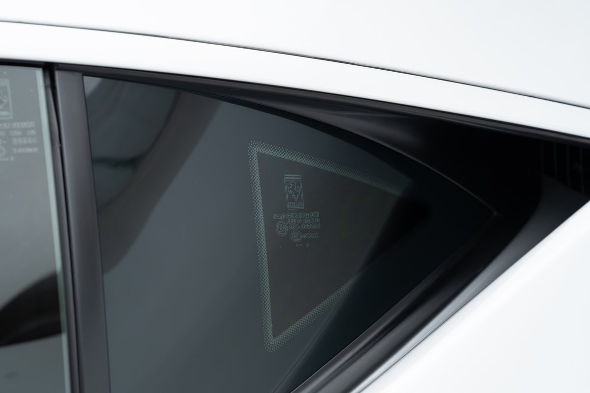 Detail of the Ferrari emblem etched onto the quarter glass of a white 2015 Ferrari 458 Speciale.