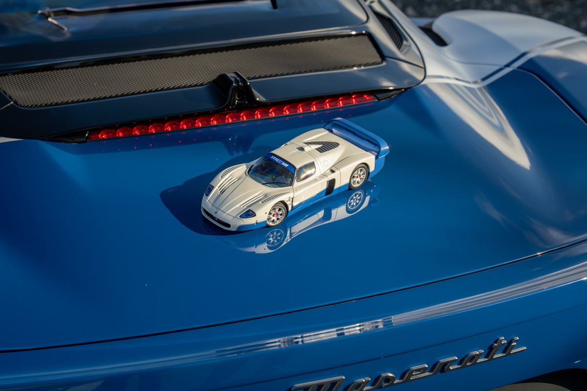 White Maserati MC20 Icona model car on a blue Maserati with white stripe livery.