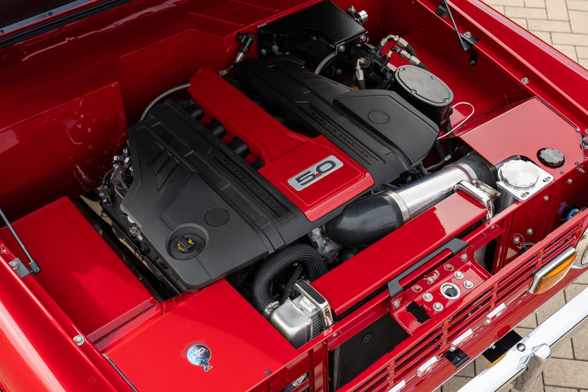 Red 1966 Ford Bronco engine bay with Ford 5.0 Coyote V8 engine swap and custom intake.