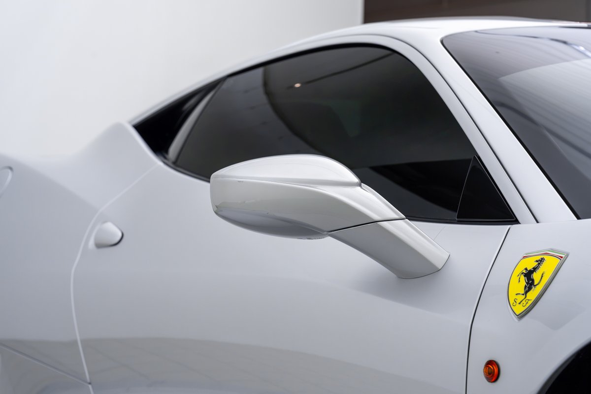 White 2015 Ferrari 458 Speciale with prancing horse emblem and tinted windows.