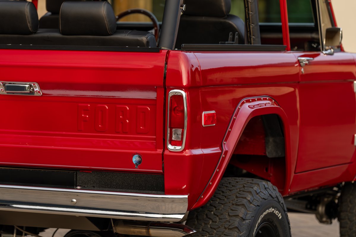Close-up of a red 1966 Ford Bronco with chrome trim and off-road tires.