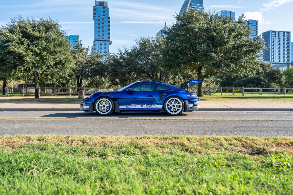 Blue 2025 Porsche 911 GT3 RS with white "GT3 RS" livery and white center-lock rims.