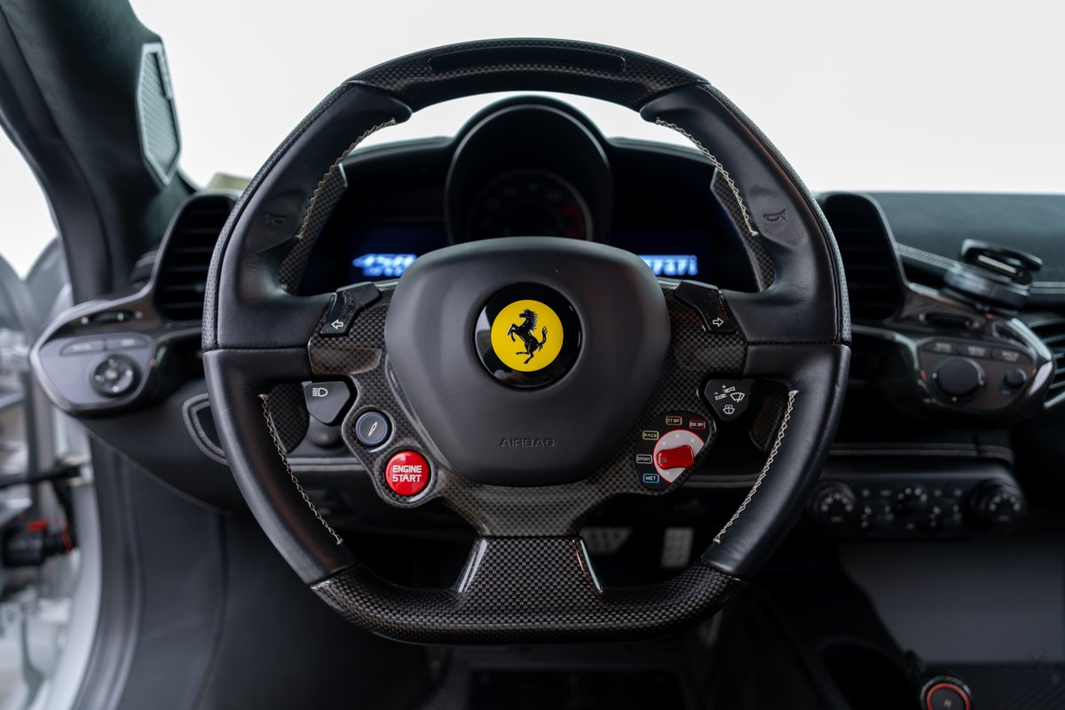 2015 Ferrari 458 Speciale interior: Carbon fiber steering wheel with yellow Cavallino Rampante badge, red engine start button.