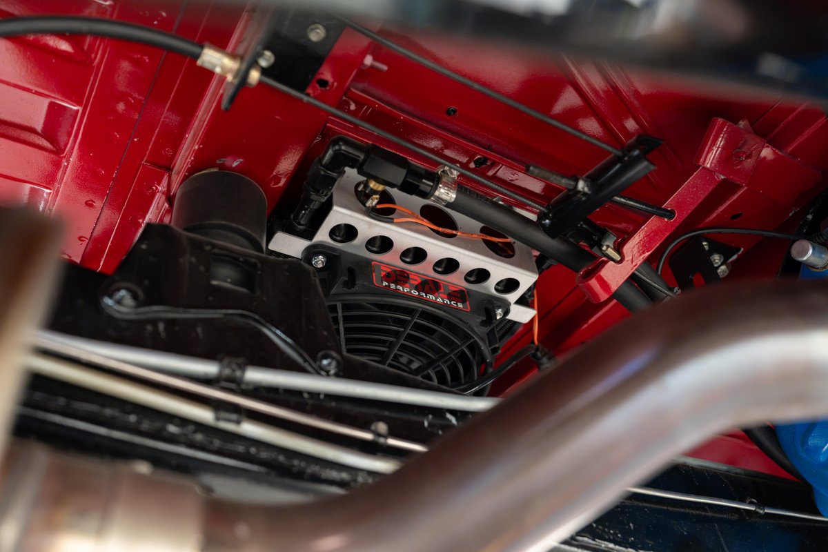 Close-up of an electric cooling fan under a red 1966 Ford Bronco, with "B&M Performance" logo.