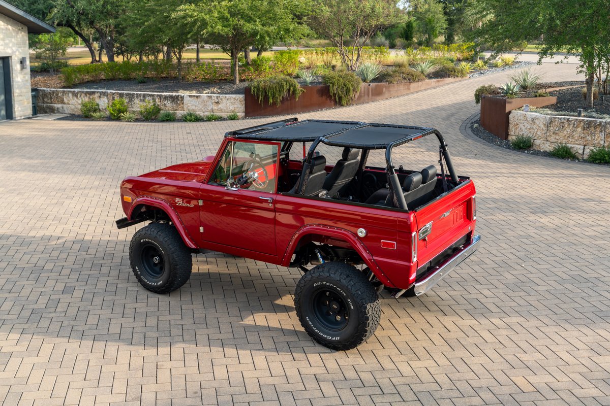 Red 1966 Ford Bronco by Atlas Broncos with black canvas top and off-road tires on black rims.