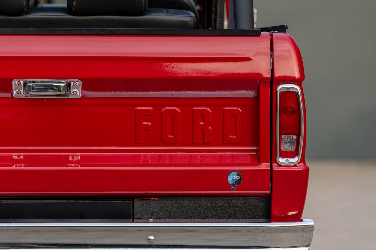 Close-up of the red tailgate on a 1966 Ford Bronco. The "FORD" lettering is embossed.