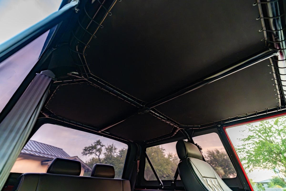 Interior view of a custom black soft top on a red 1966 Ford Bronco.