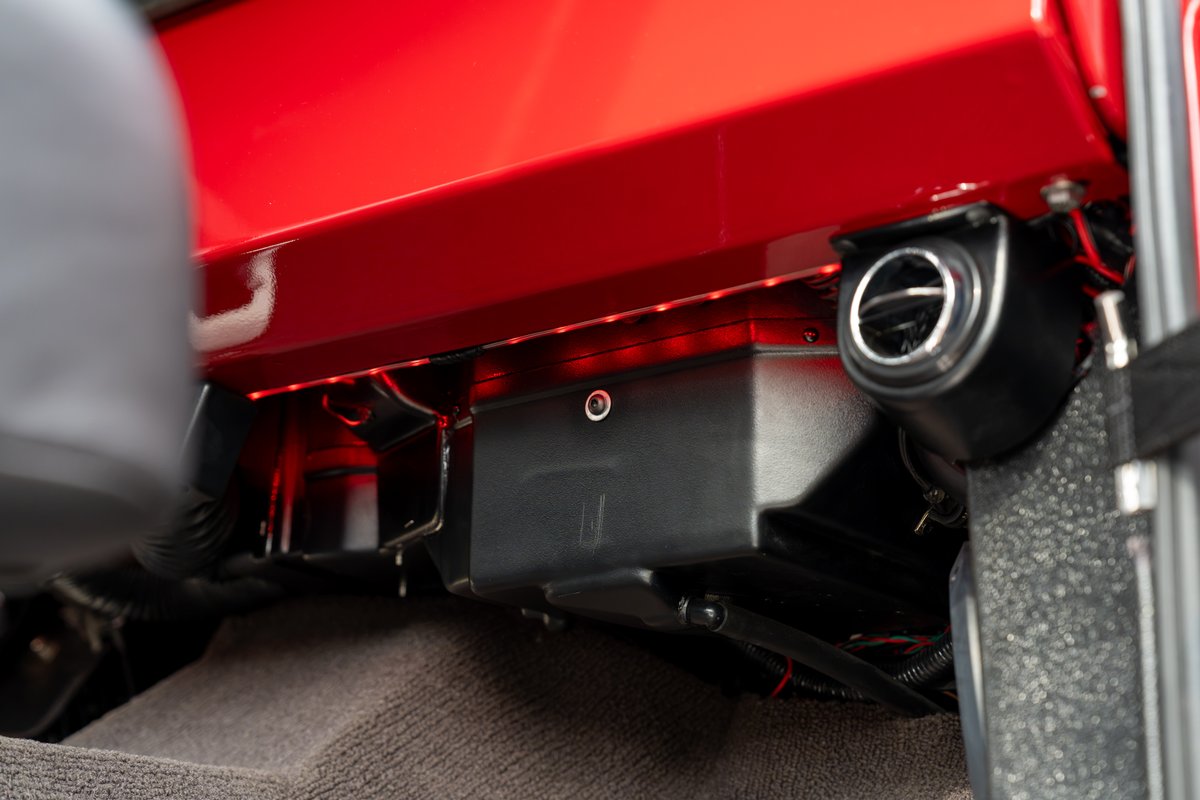 1966 Ford Bronco interior with red ambient lighting, black trim, and a chrome vent.