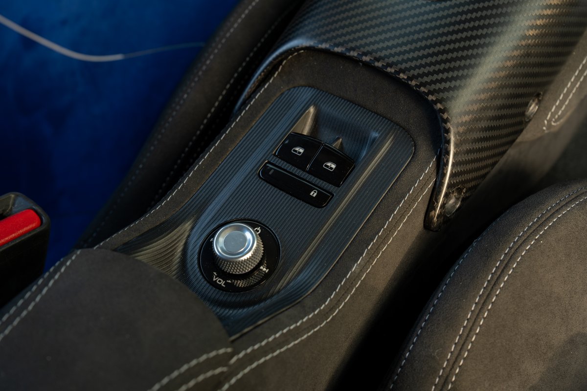 2024 Maserati MC20 Icona interior: carbon fiber trim, Alcantara, volume dial, and window/lock controls.