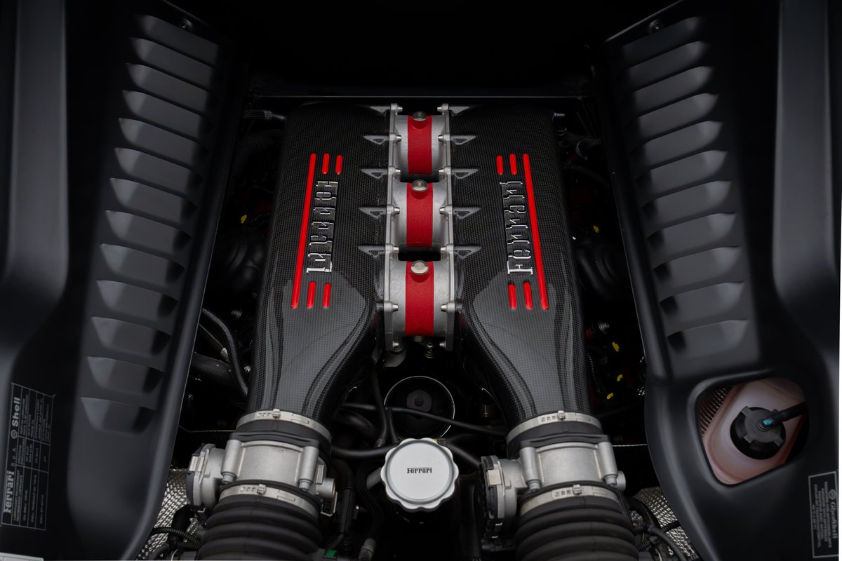 Close-up of a Ferrari 458 Speciale engine bay, featuring carbon fiber engine covers with red Ferrari livery.