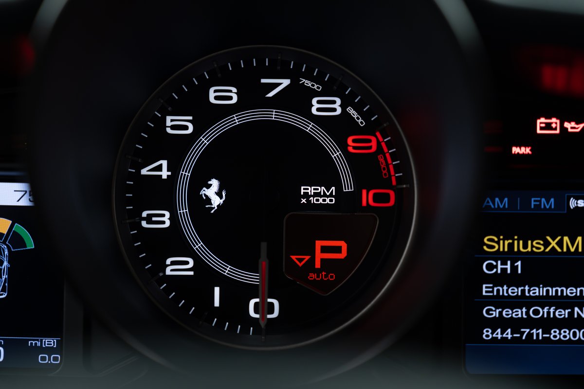 Close-up of a 2015 Ferrari 458 Speciale's tachometer and digital display, showing RPM and Park mode.