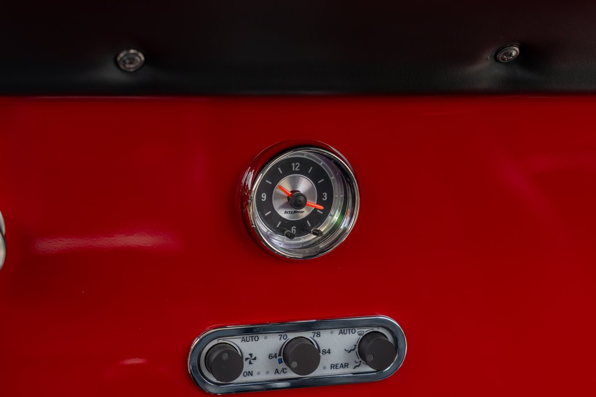 Classic 1966 Ford Bronco interior: red dash, chrome-bezeled clock, and climate controls.