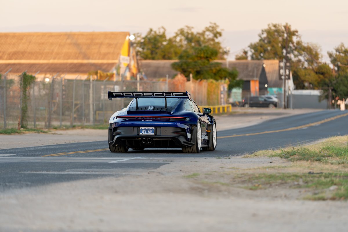 2025 Porsche 911 GT3 RS in blue with a large rear wing and white rims.