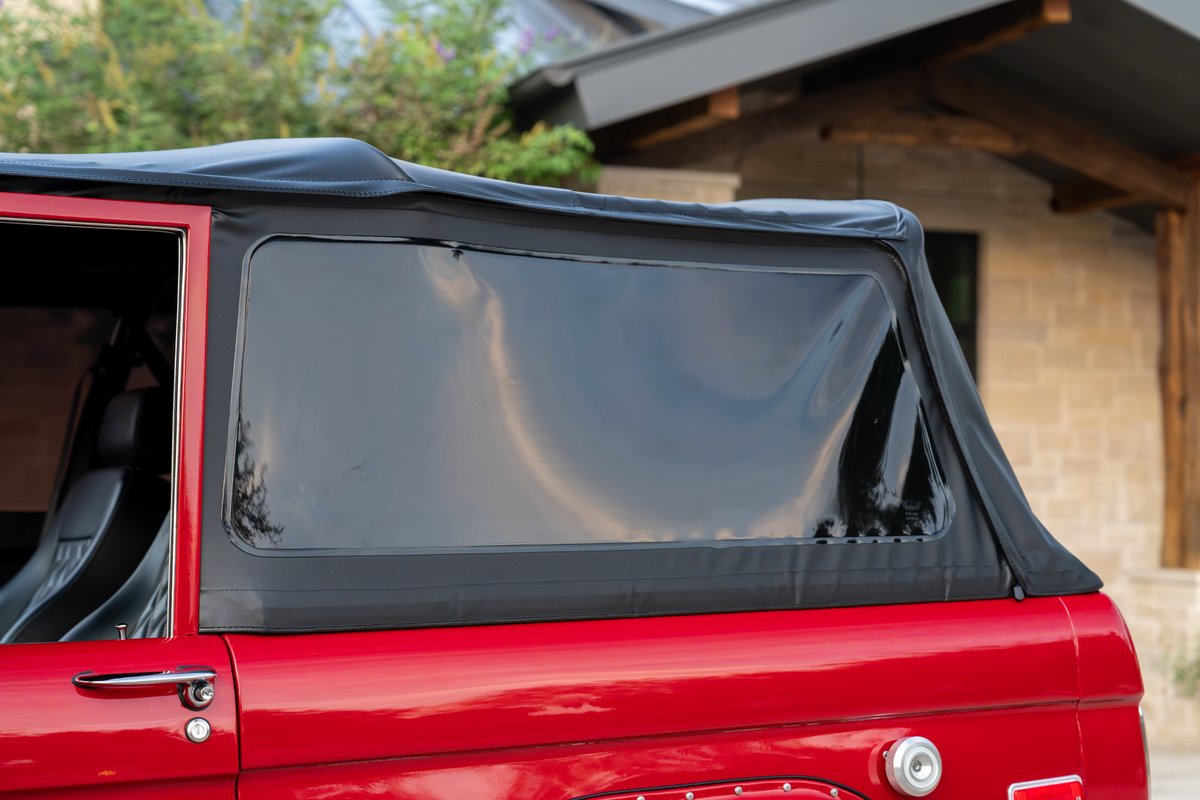 1966 red Ford Bronco by Atlas Broncos with a black soft top and clear side windows.