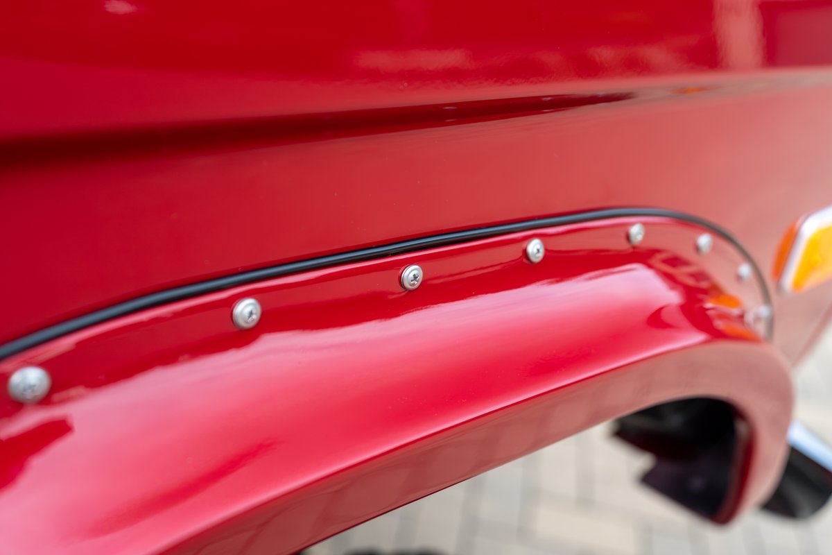 Red 1966 Ford Bronco with riveted fender flares and black trim detail.