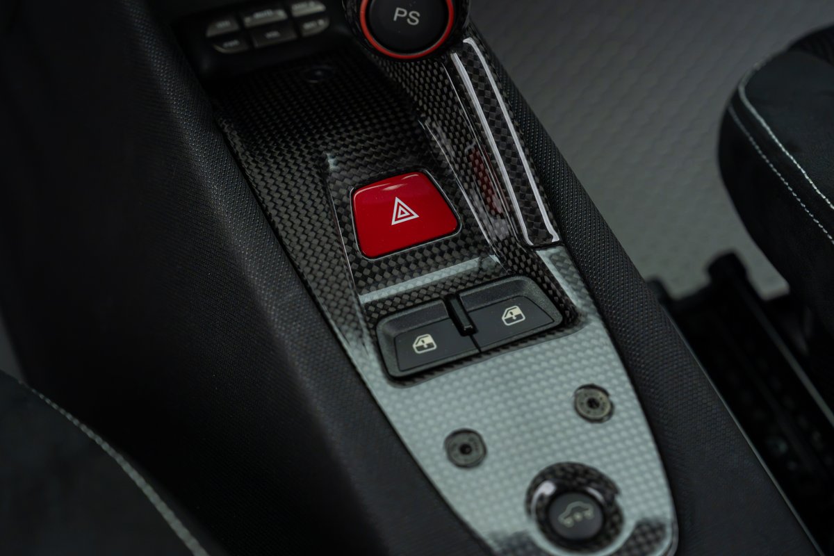 2015 Ferrari 458 Speciale interior with carbon fiber trim, red hazard button, and window controls.