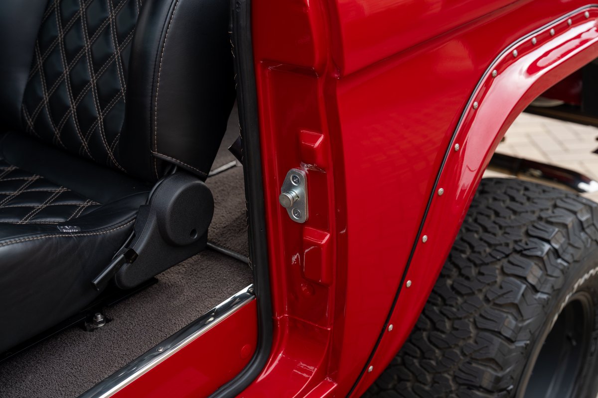 1966 Ford Bronco by Atlas Broncos: Red paint, diamond-stitched black leather seats, and fender flares with rivets.