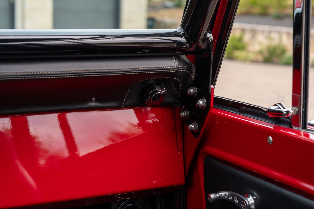 Red 1966 Ford Bronco interior: custom dash trim, black leather seats, roll cage.