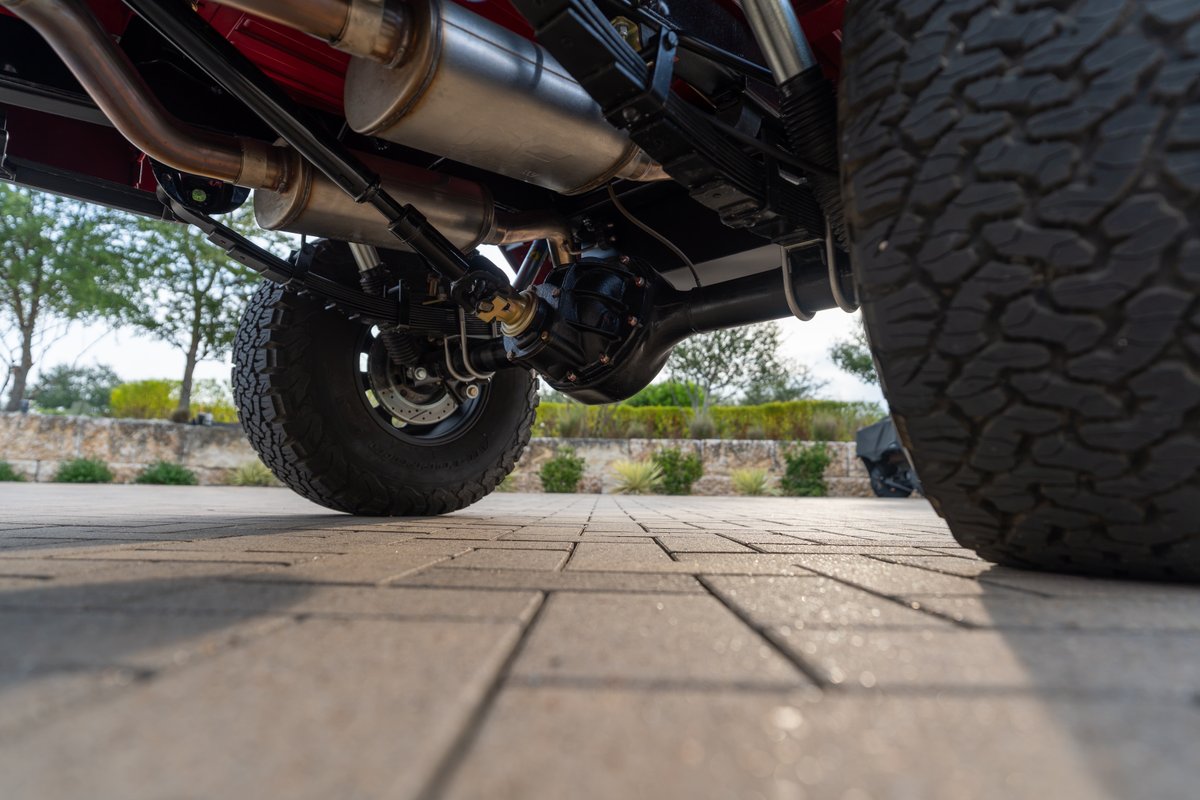 1966 Ford Bronco rear axle, leaf springs, dual exhaust, and rugged tires.