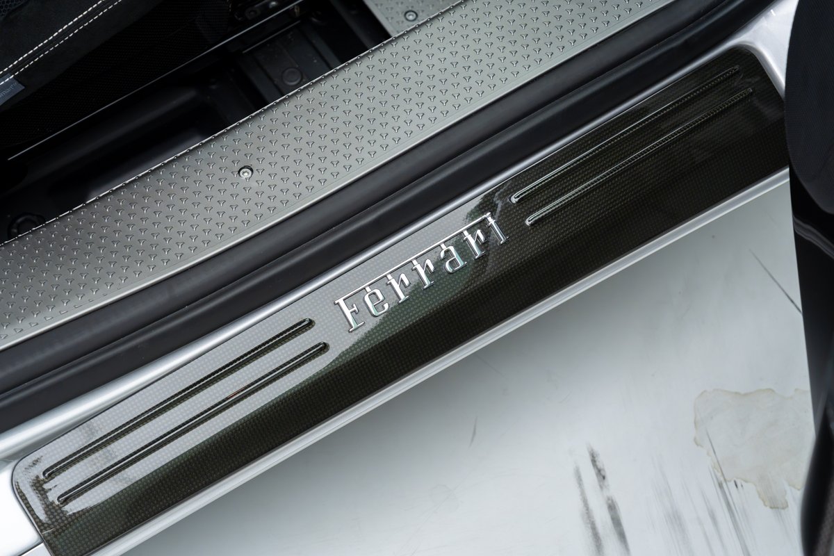Close-up of 2015 Ferrari 458 Speciale's carbon fiber door sill trim with silver Ferrari badging.