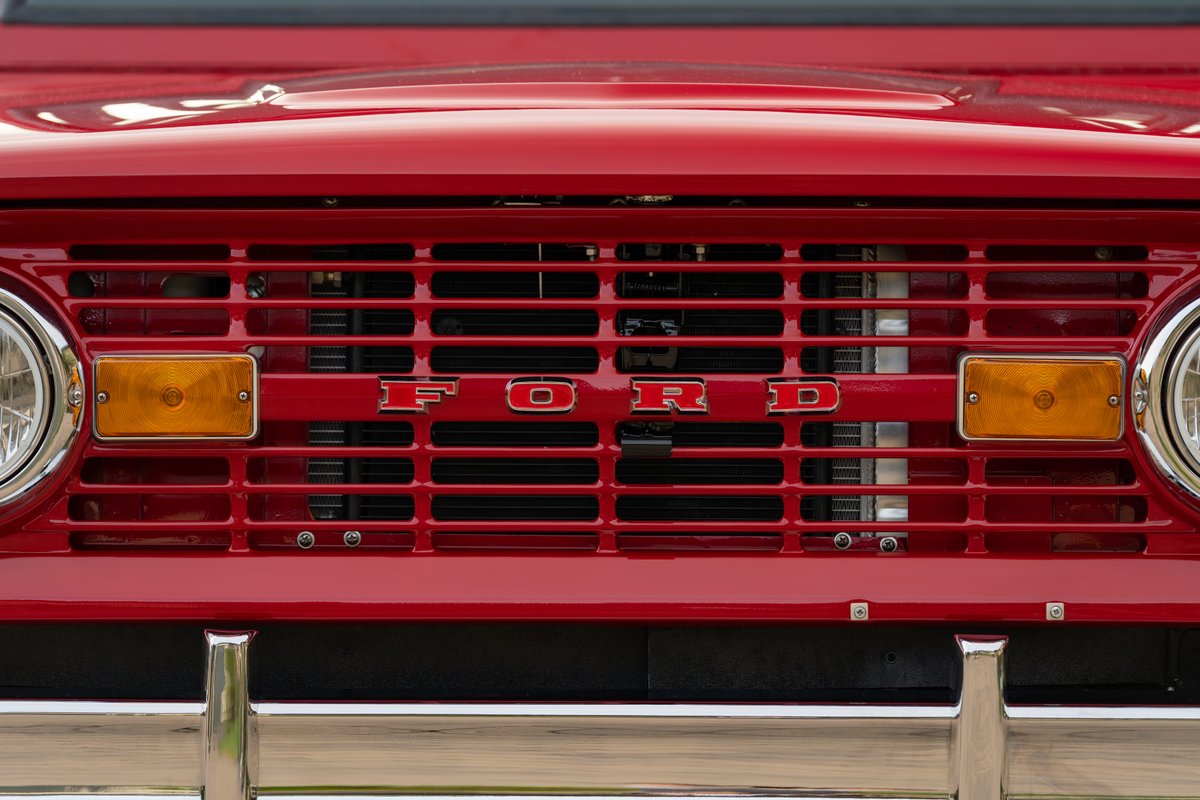 Front grill of a red 1966 Ford Bronco, featuring iconic "FORD" badging.