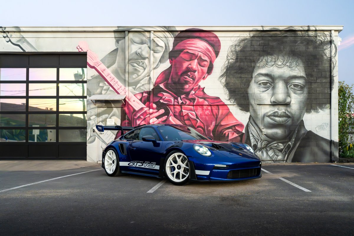 A blue 2025 Porsche 911 GT3 RS with white multi-spoke rims and side livery.