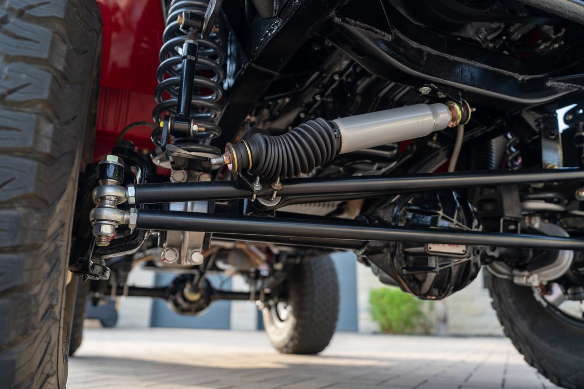 Close up of the heavy-duty suspension and steering components on a red 1966 Ford Bronco.