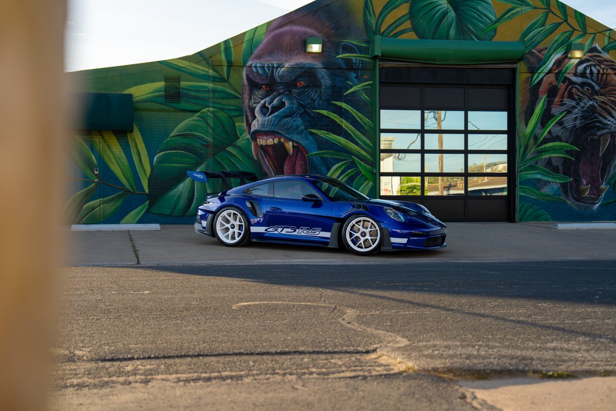 A blue 2025 Porsche 911 GT3 RS with white center-lock rims and side decal livery.